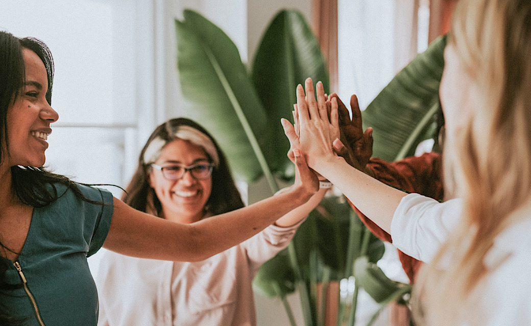 Positive and ethical teamwork, women high-fiving each other, smiling faces