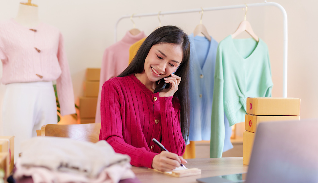 Young woman who owns an online business takes orders from customers and prepares parcel boxes for customers to call and talk to customers to confirm pickup. Retail procurement