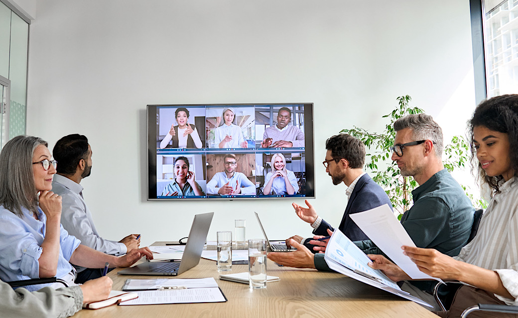 Diverse company employees having online business conference video call on tv screen monitor in board meeting room. Videoconference presentation, global virtual group corporate training